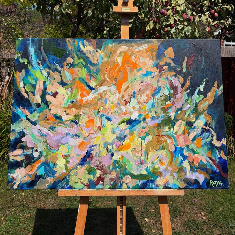 Abstract painting on an easel outdoors with trees in the background