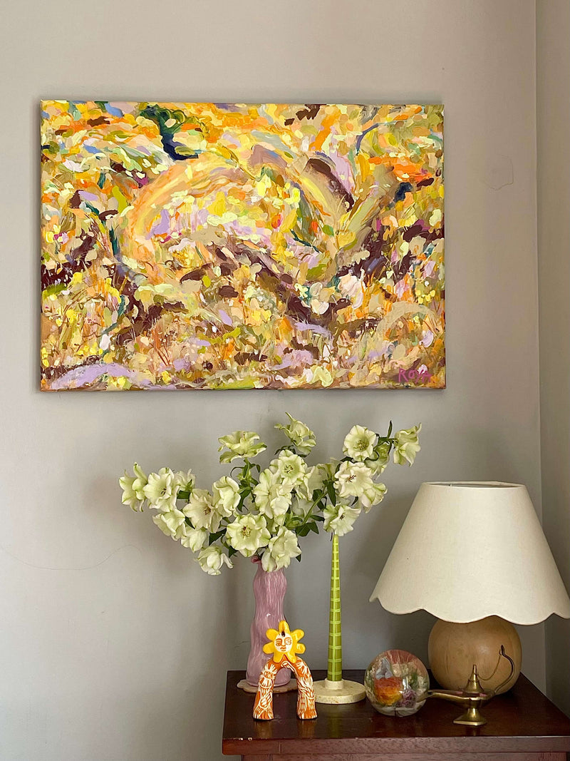 Abstract painting on a wall above a table with decorative items.