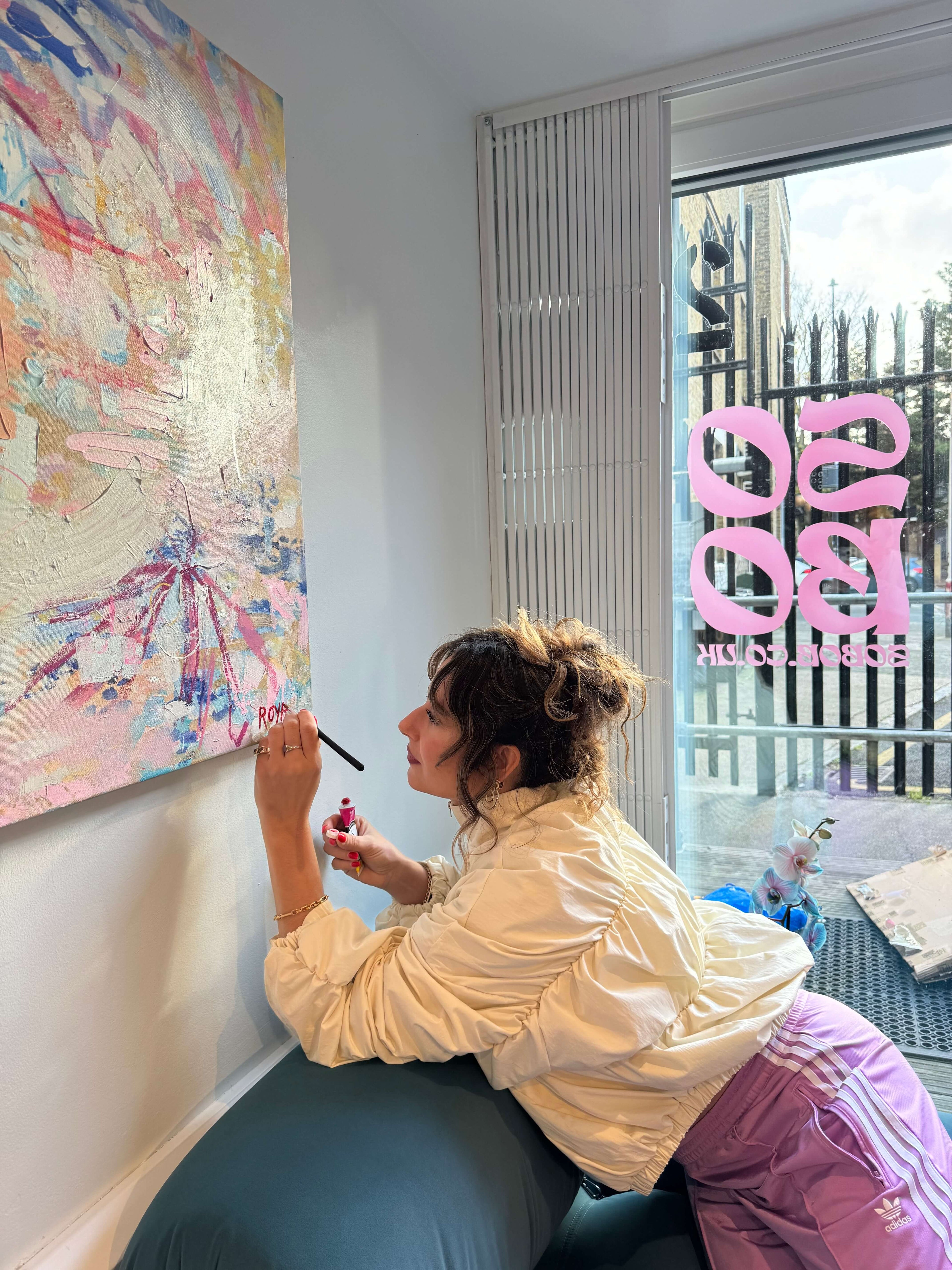 Sara painting a colourful abstract artwork on a wall.